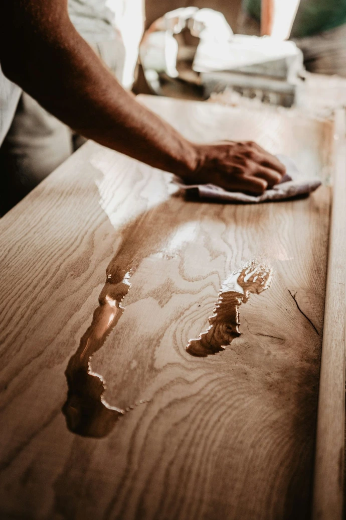 a person renovating a wooden table with a cloth